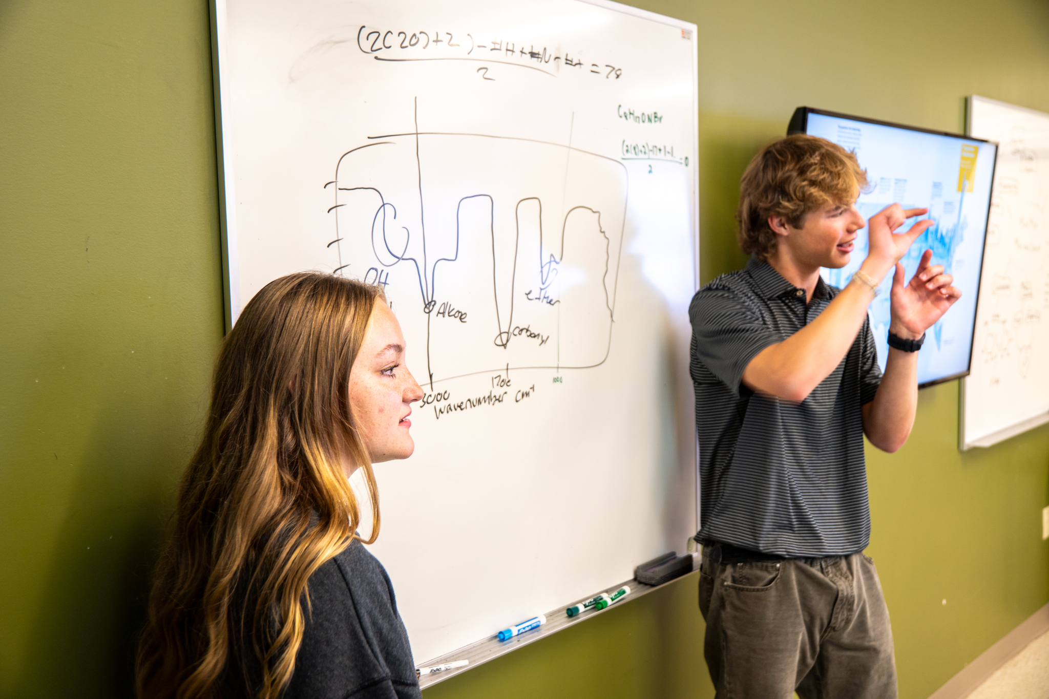 Two students presenting in front of whiteboard
